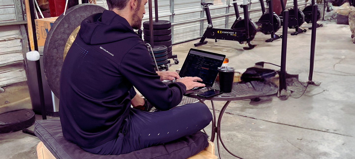 A man sitting cross-legged at a bistro table in a warehouse gym