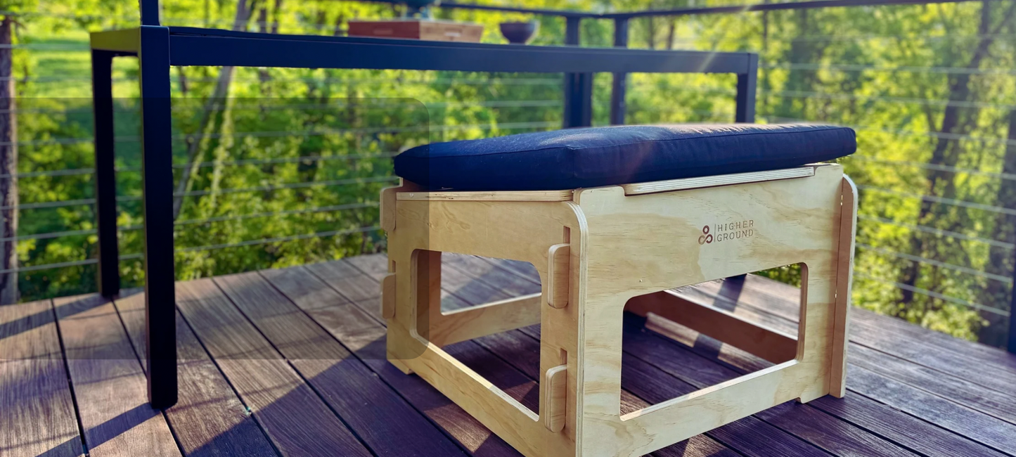 Higher ground chair for active sitting on a deck in front of a table with foliage in the background