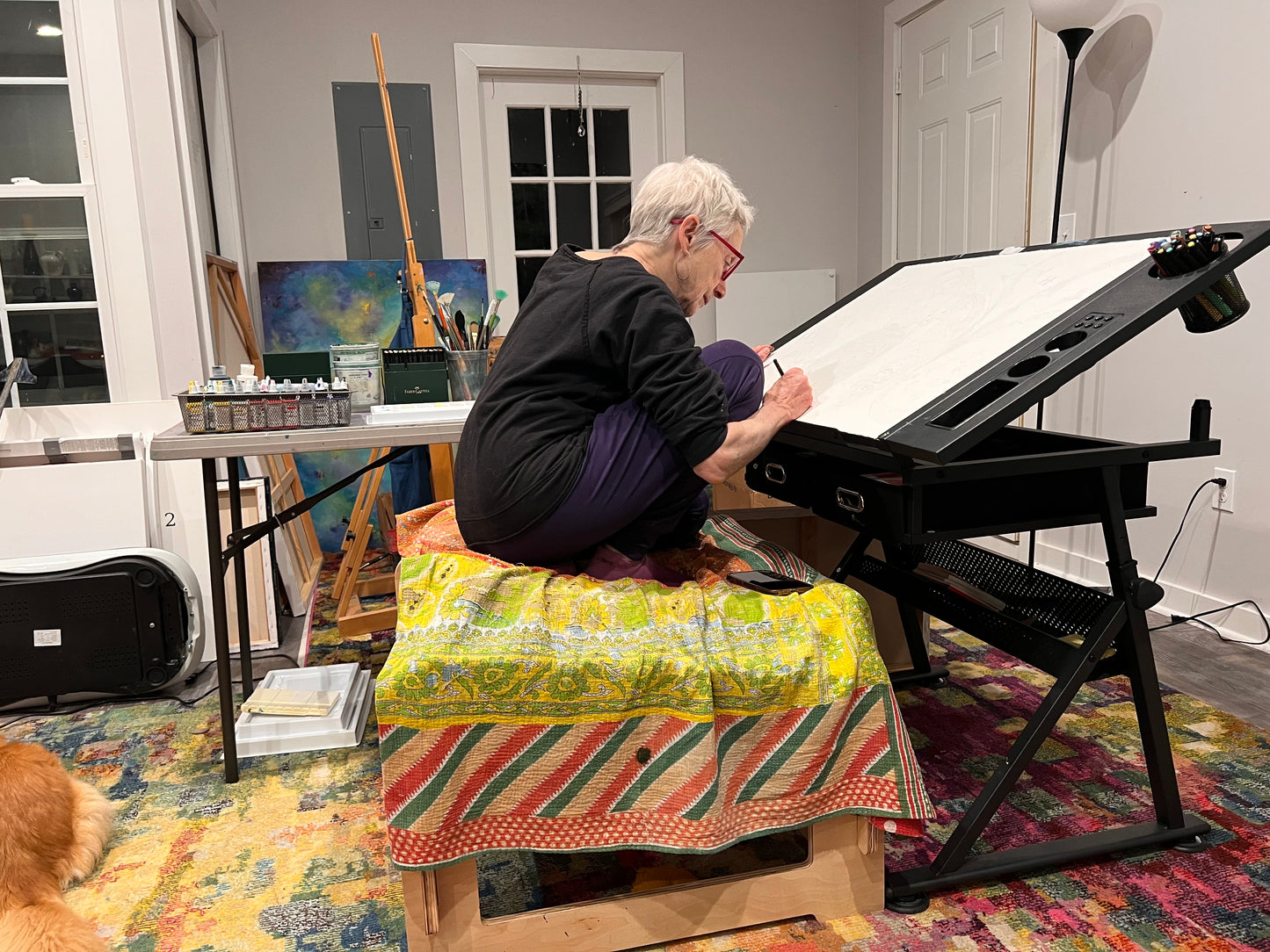 Artist painting while actively sitting on higher ground chair