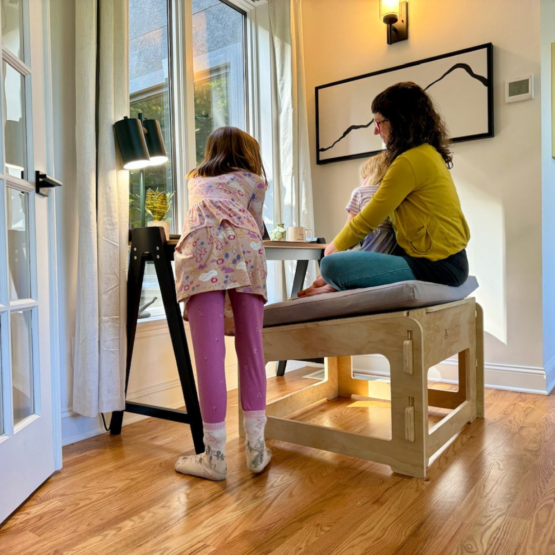 Mother and daughter sitting on a higher ground chair with an older child standing next to them