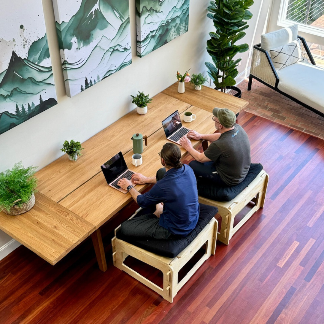 Two men seen from above sitting actively at a work table