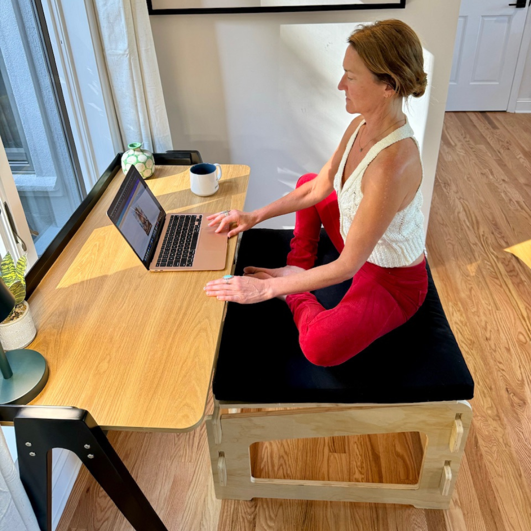 Woman sitting with soles of feet together on higher ground chair and black cushion